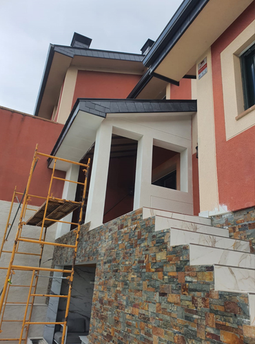 Fachada de chalet reformada con escalera de piedra