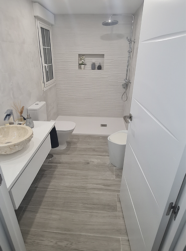Baño reformado con ducha de obra y acabados blancos